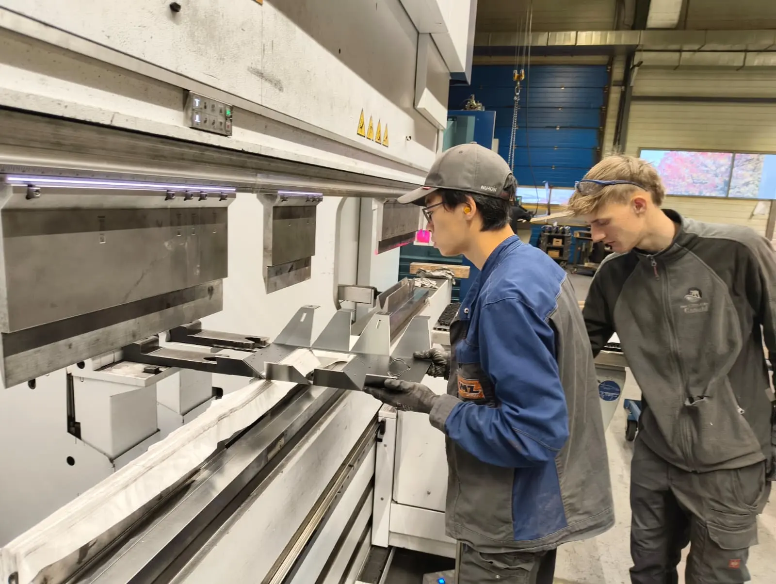Peng und Philipp beim gemeinsamen Biegen der Werkstücke an der Kantmaschine